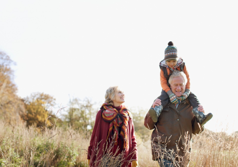 Grand-parents se promenant dans la nature avec leur petit-fils sur les épaules du grand-père